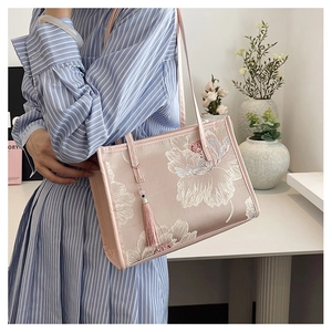 Detail of pink satin tote bag featuring intricate flower embroidery and silk tassel