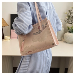 Close-up of pink tote bag featuring elegant floral embroidery and a matching tassel