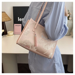 Detailed close-up of pink floral embroidery tote bag with silk tassel in a lifestyle setting