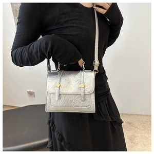 Détail d'un sac argenté métallisé plissé avec garnitures dorées et bandoulière réglable