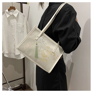 Detail of floral embroidery and green tassel on an off-white Chinese style tote bag