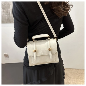 Vue détaillée du sac à main en cuir plissé blanc avec boucles dorées sur un mannequin