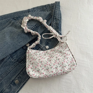 Floral print shoulder bag with ruched strap and bow detail on a blue denim jacket