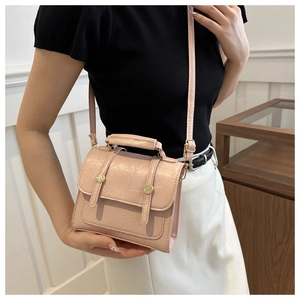 Détail d'un sac carré rose plissé avec doubles lanières et boucles dorées élégantes
