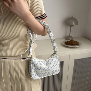 Floral shoulder bag with purple patterns and ruched handle shown on a model