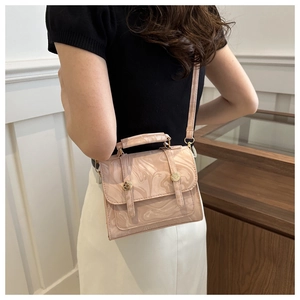 Vue détaillée du sac carré motif marbre rose avec garnitures dorées sur un mannequin