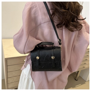 Détail du sac vintage noir avec texture craquelée unique et boutons-pression dorés