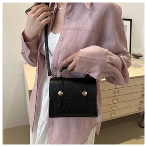 Détail du sac rétro noir avec finition texturée et boucle ronde en métal doré brillant