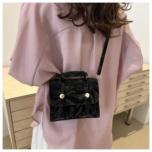 Détail du sac bandoulière en cuir verni à motif marbré noir avec boutons dorés