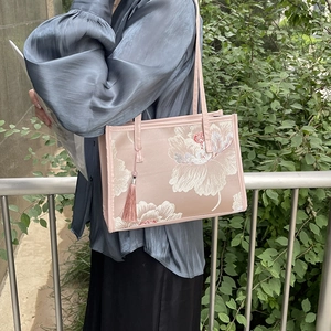 Elegant pink floral embroidered tote bag with tassel shown on model in natural light