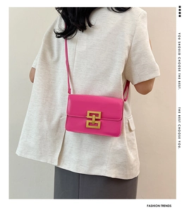 Détail du sac bandoulière fuchsia en cuir avec boucle dorée porté par un mannequin