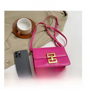 Détail du sac bandoulière rose fuchsia tendance avec boucle dorée sur un manteau beige