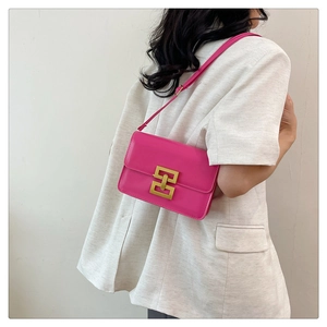 Détail d'un sac à bandoulière rose fuchsia avec fermoir géométrique doré et sangle