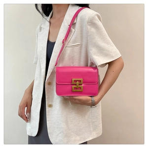 Détail d'un sac bandoulière rose avec fermoir géométrique doré sur le rabat avant