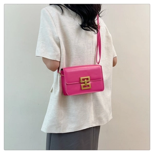 Détail d'un sac bandoulière en cuir rose avec fermoir doré porté par un mannequin