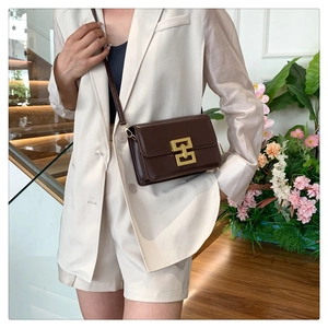 Détail du sac bandoulière en cuir marron foncé avec une boucle en métal doré géométrique
