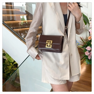 Détail d'un sac bandoulière marron en similicuir avec boucle métallique dorée chic