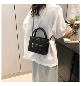 Side view of black crocodile pattern crossbody bag showing size and textured finish