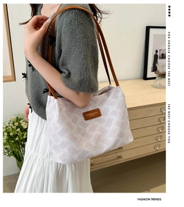 Detail of a large woven tote bag with brown leather straps and geometric pink patterns