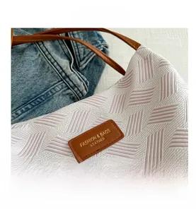Close-up of white woven fabric texture with pink geometric patterns and brown leather logo