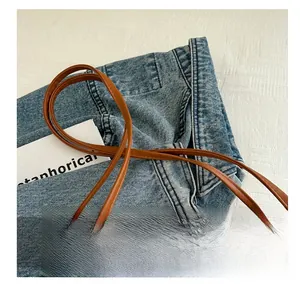 Detail of white geometric texture on tote bag with brown leather handle and jeans