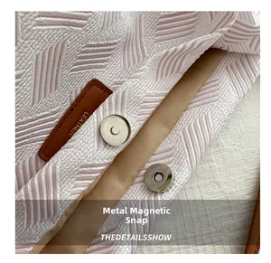 Detail view of pink woven fabric texture with leather patch and metal magnetic buckle