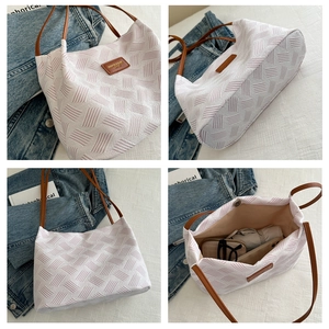 Detail view of woven tote bag texture with leather logo tag and spacious interior
