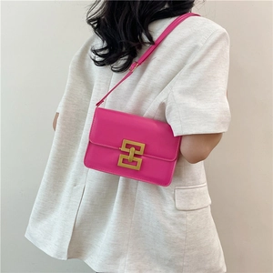 Sac bandoulière en cuir magenta avec fermoir H doré, porté par un mannequin en veste