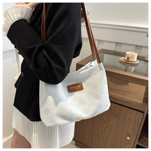 Detail of light blue shoulder bag with geometric woven texture and leather strap