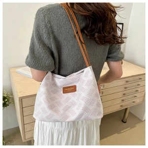 Close-up of pink jacquard shoulder bag with embossed geometric texture and leather straps