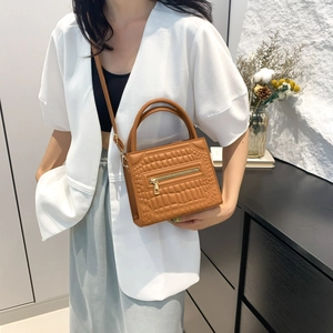 Brown crocodile embossed leather handbag with gold zipper and shoulder strap on a model