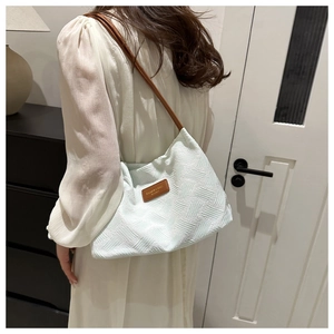 Detail of mint green woven shoulder bag with brown leather strap on model back