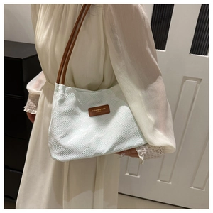 Detail of mint green pleated fabric shoulder bag with contrasting brown leather handles