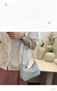 Close-up of light blue underarm bag with navy floral print and silver chain strap