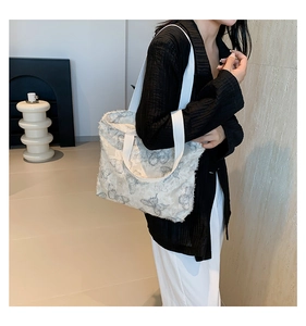 Detail of white tote bag with textured tassel fabric and gray butterfly embroidery