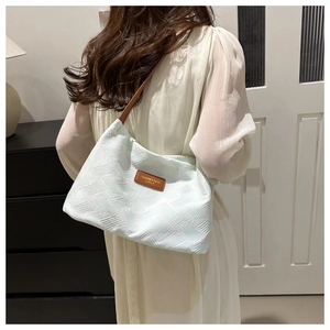 Detail of mint green pleated shoulder bag with brown leather strap and logo plate