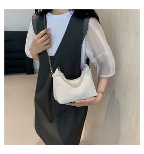 Close-up of a white pearl-handle shoulder bag with elegant gold metal chain and matte finish