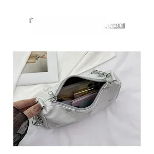 Detail of white embroidered shoulder bag showing interior space for phone and makeup