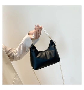 Detail of black crescent moon bag with pearl handle and golden chain strap for women