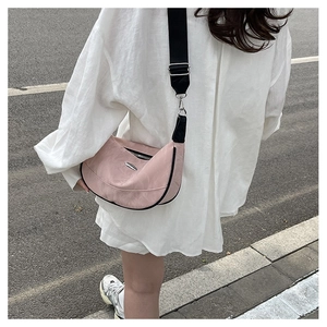 Detailed shot of a pink crescent crossbody bag with black nylon strap and metal logo