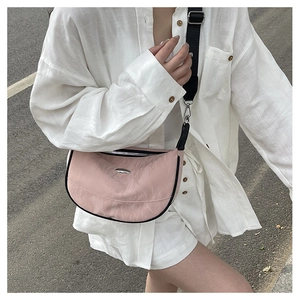 Pink crescent crossbody bag with black trim and adjustable wide strap on model