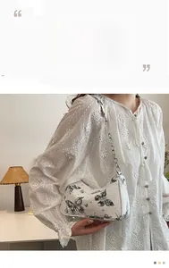 Détail d'un sac à bandoulière vintage blanc avec imprimés papillon noirs et chaîne argent