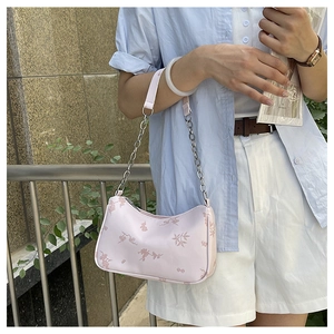 Detail of light pink shoulder bag with floral prints and silver metal chain strap