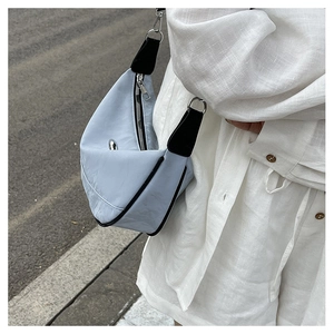Close-up of a blue crescent handbag with fine pleats and black shoulder strap detail
