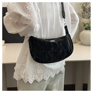 Close-up of black crescent crossbody bag with textured fabric and adjustable strap