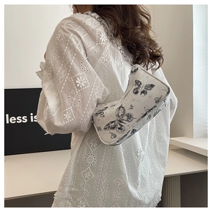 Détail d'un sac à bandoulière blanc avec imprimés papillons et bandoulière chaîne argentée