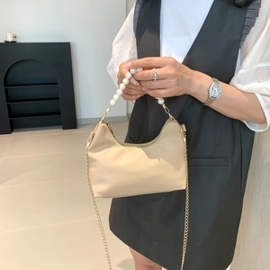 Elegant beige pearl chain hobo bag with gold hardware shown on a minimalist model