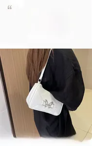 Dettaglio della borsa a spalla bianca con fibbia a farfalla argentata indossata da modella
