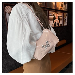 Borsa sottobraccio in pelle verniciata rosa con un ornamento a farfalla in metallo