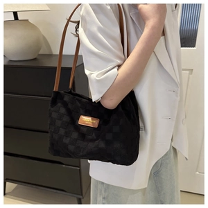 Détail d'un cabas à damier avec anses en cuir marron et étiquette de mode gravée